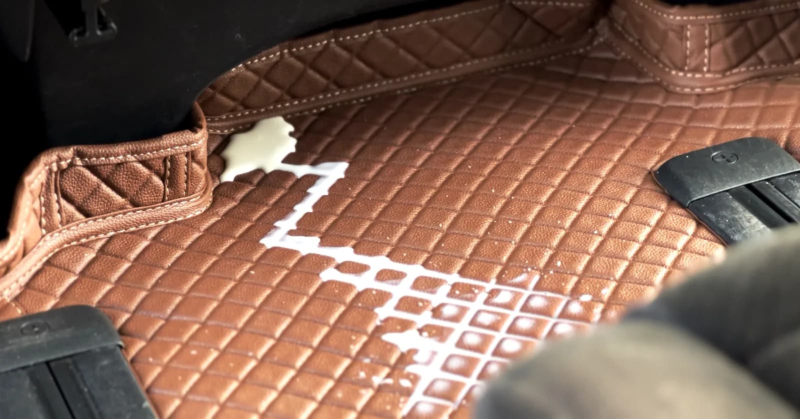 Spilt milk sitting on top of a brown 3D car mat in the rear footwell, held inside its raised edge
