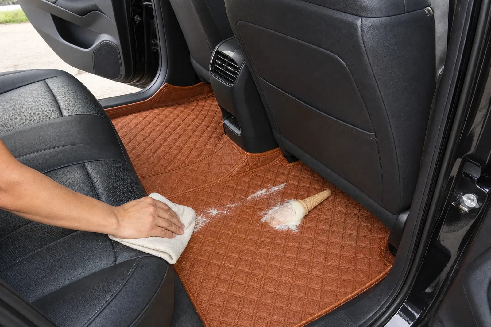 A cloth wiping a dropped ice cream off the rear Porsche Orange 3D car mat