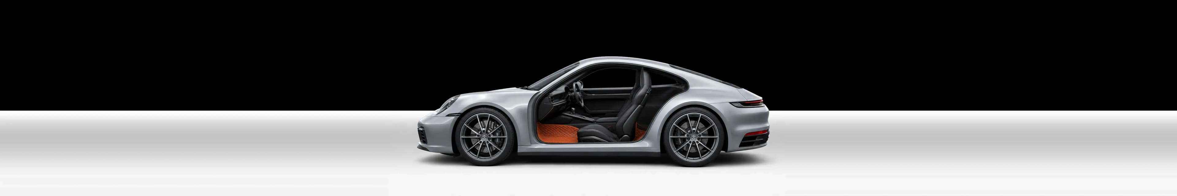Cut-away of a silver two-seater sports car showing a Porsche Orange 3D car mat in the footwell