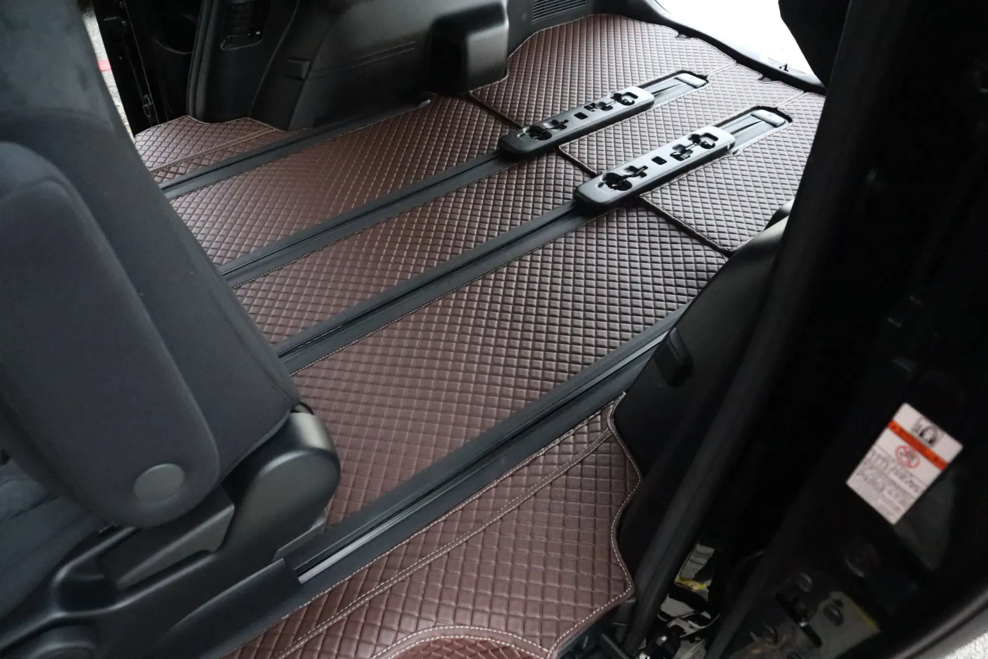MPV seat rails with a brown 3D car mat fitted between them