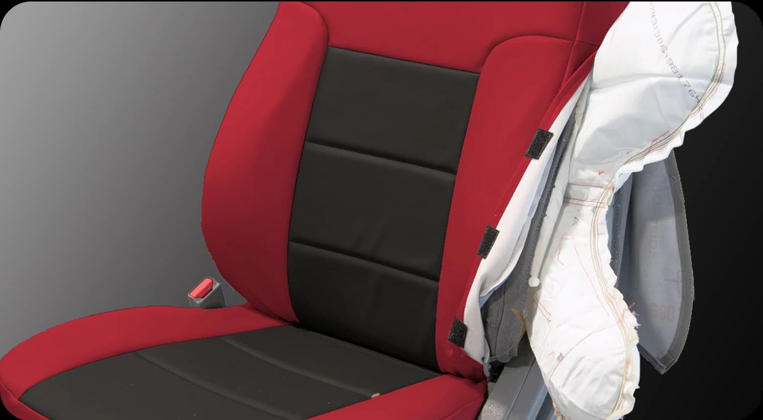 A seat airbag deployed through the seam of a red and black seat cover