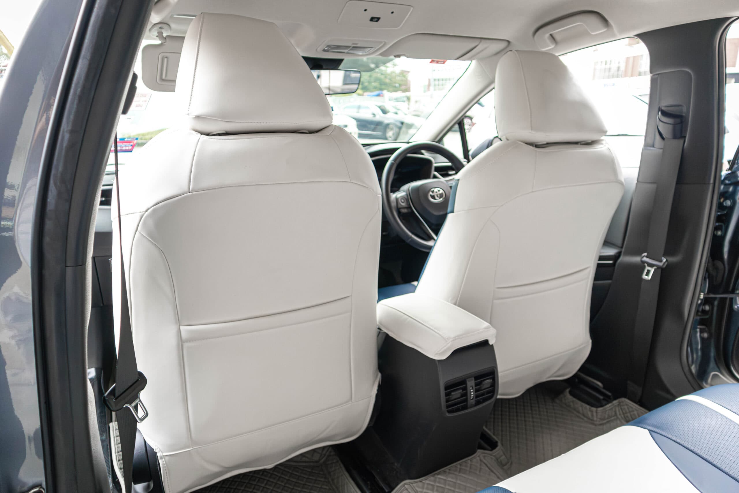 Backs of both front seats in white, seen through the open rear door