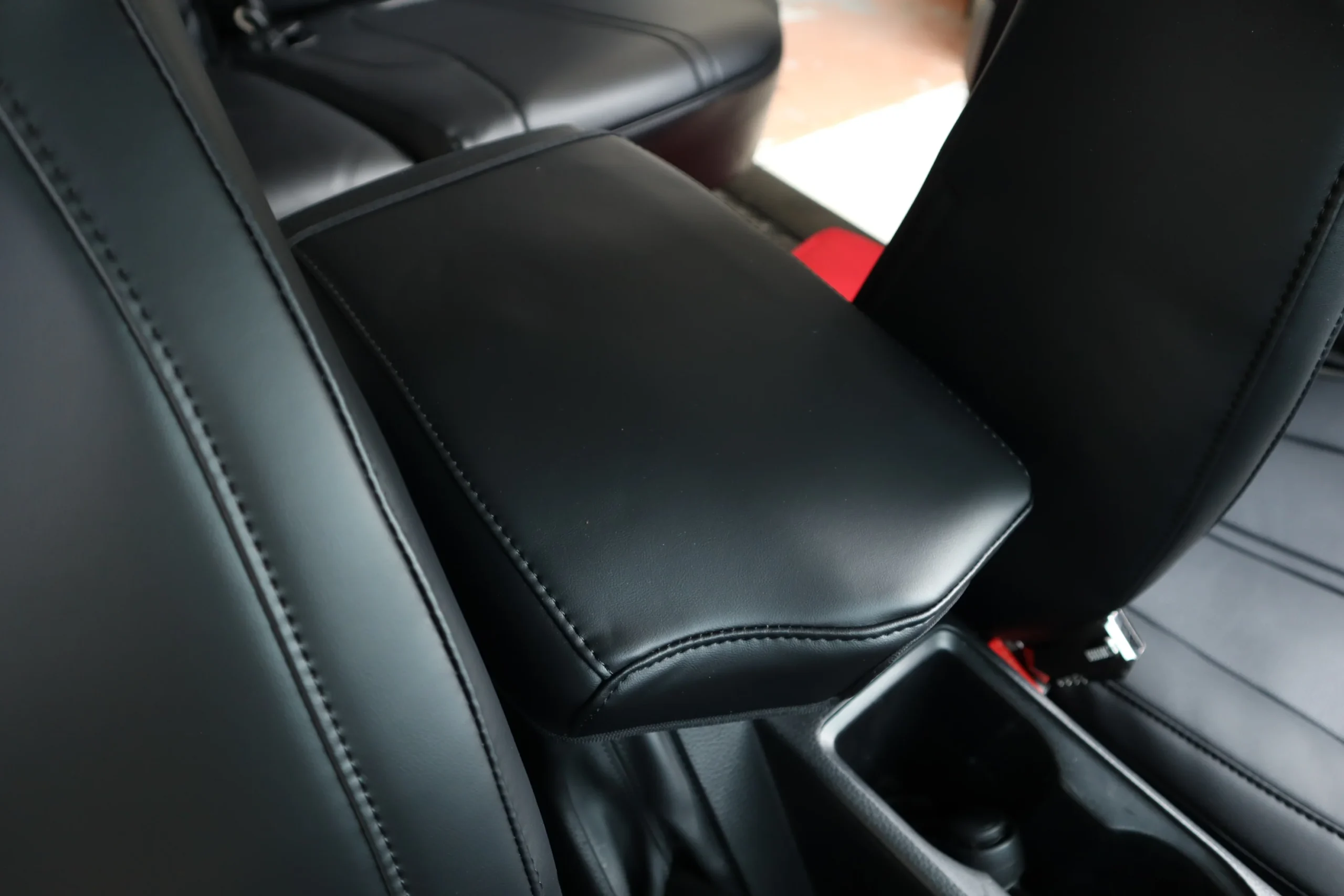 Centre armrest of a black Titan set, covered and stitched to the same shape