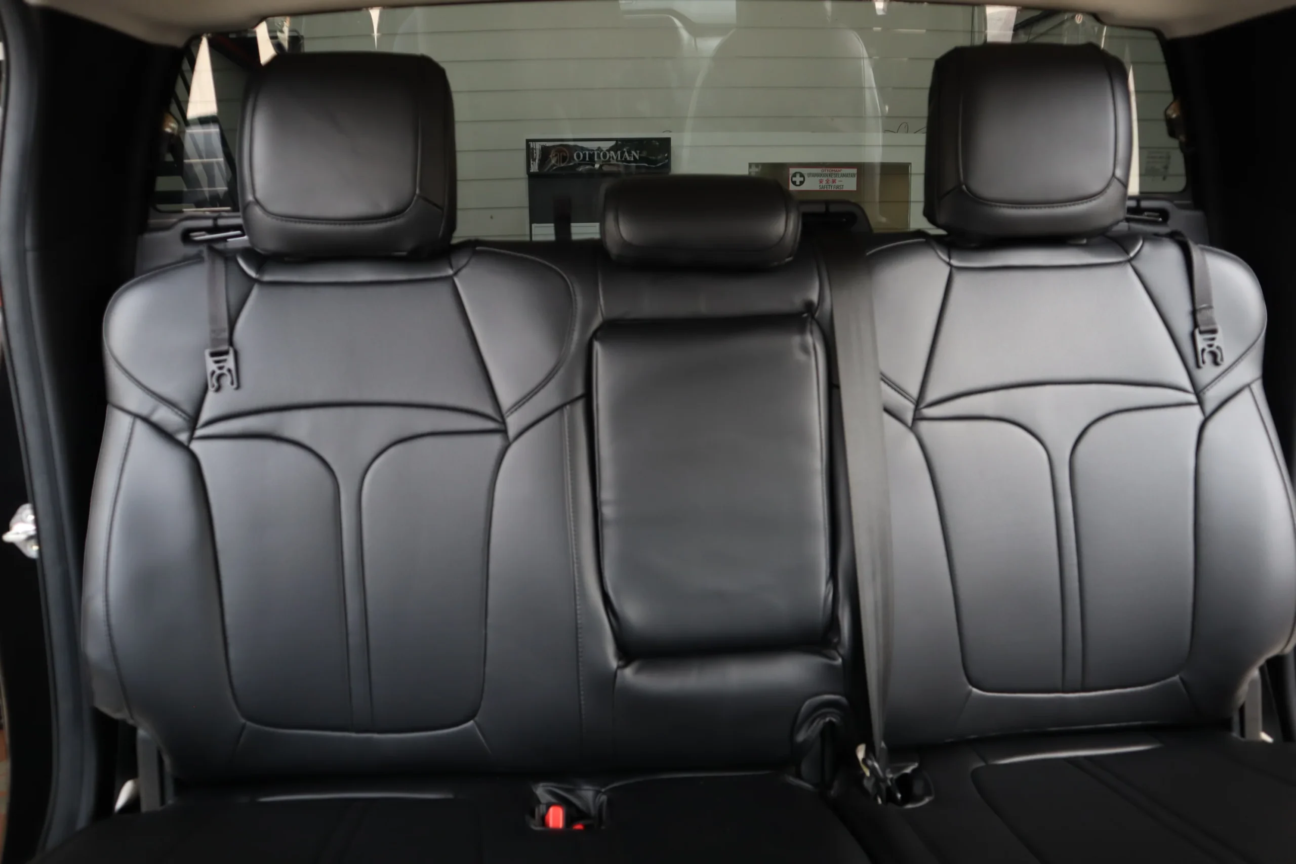 Rear bench in black Titan covers seen head-on, the T on both outer backrests